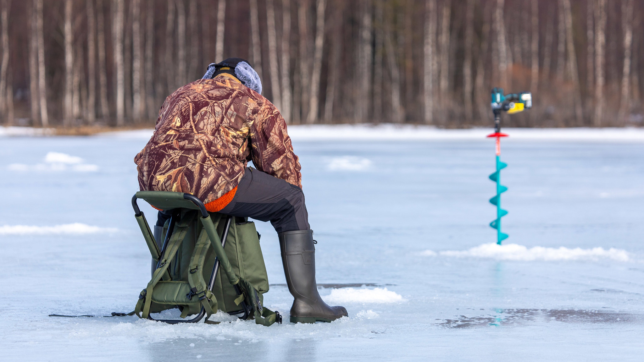 Pilkkimies istuu reiän äärellä Aittojärvellä