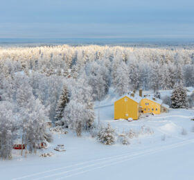 Keltainen talo kuuraisessa maisemassa ilmasta kuvattuna