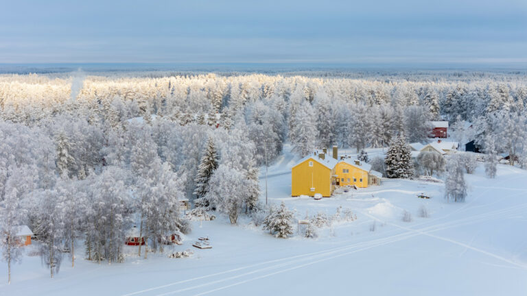 Keltainen talo kuuraisessa maisemassa ilmasta kuvattuna