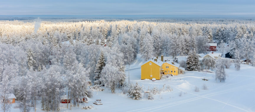 Keltainen talo kuuraisessa maisemassa ilmasta kuvattuna
